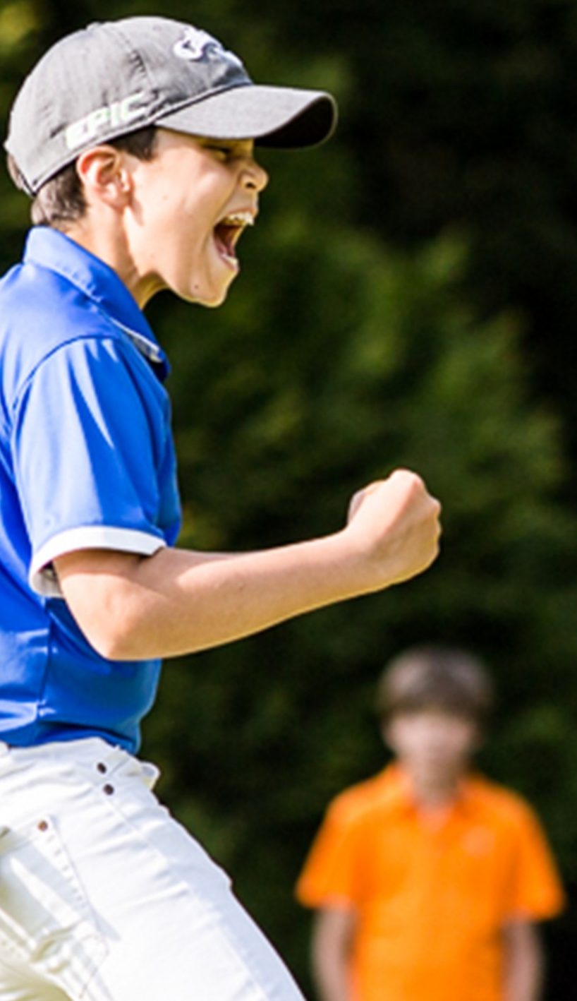 A junior golfer celebrating a putt