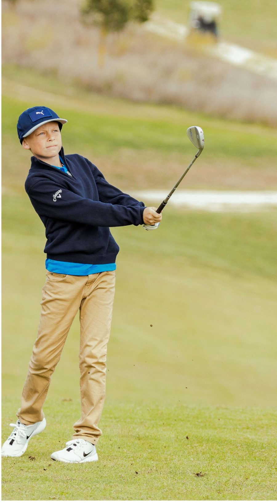 A junior golfer watching his approach shot